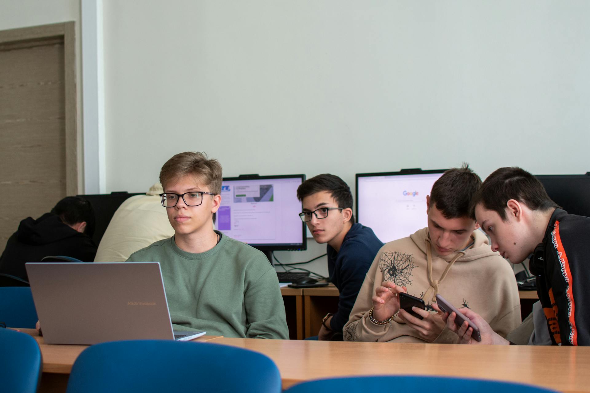 Students using laptops and smartphones in a modern classroom. Photo by Mikhail Nilov on Pexels