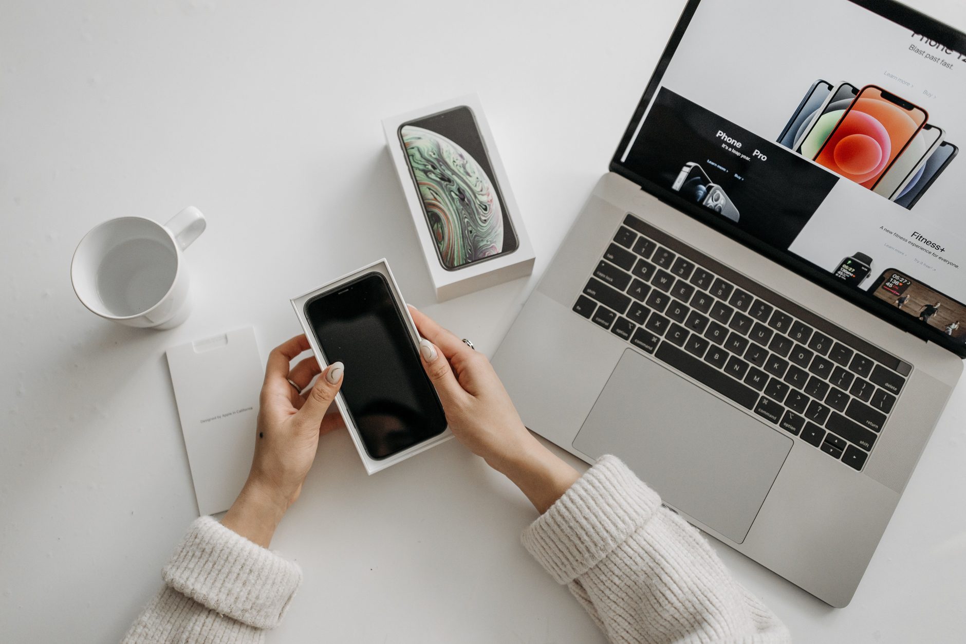 A new smartphone taken out of its box next to a laptop, ready to enroll on first boot