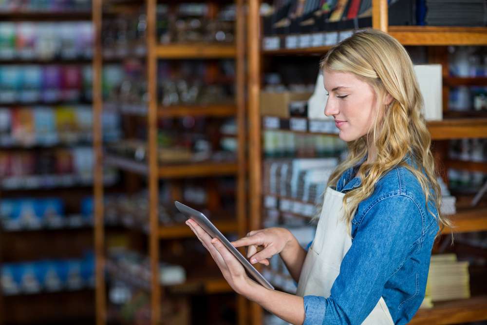 Employée souriante utilisant une tablette kiosk dans un supermarché