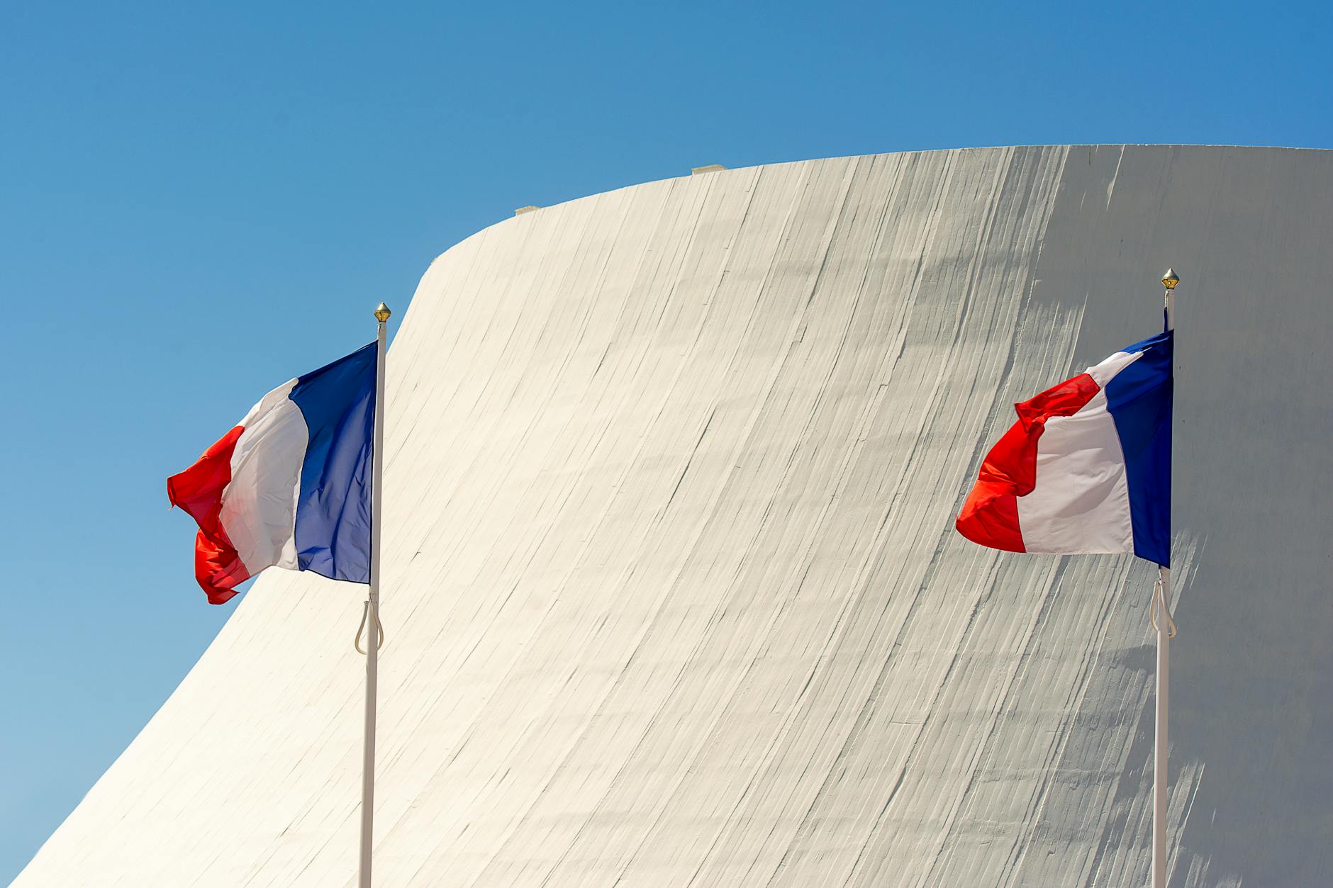 Drapeaux français devant une architecture moderne : la souveraineté du MDM se joue dans l'actionnariat et l'hébergement, pas seulement dans la plaquette. Photo par Jan van der Wolf sur Pexels.