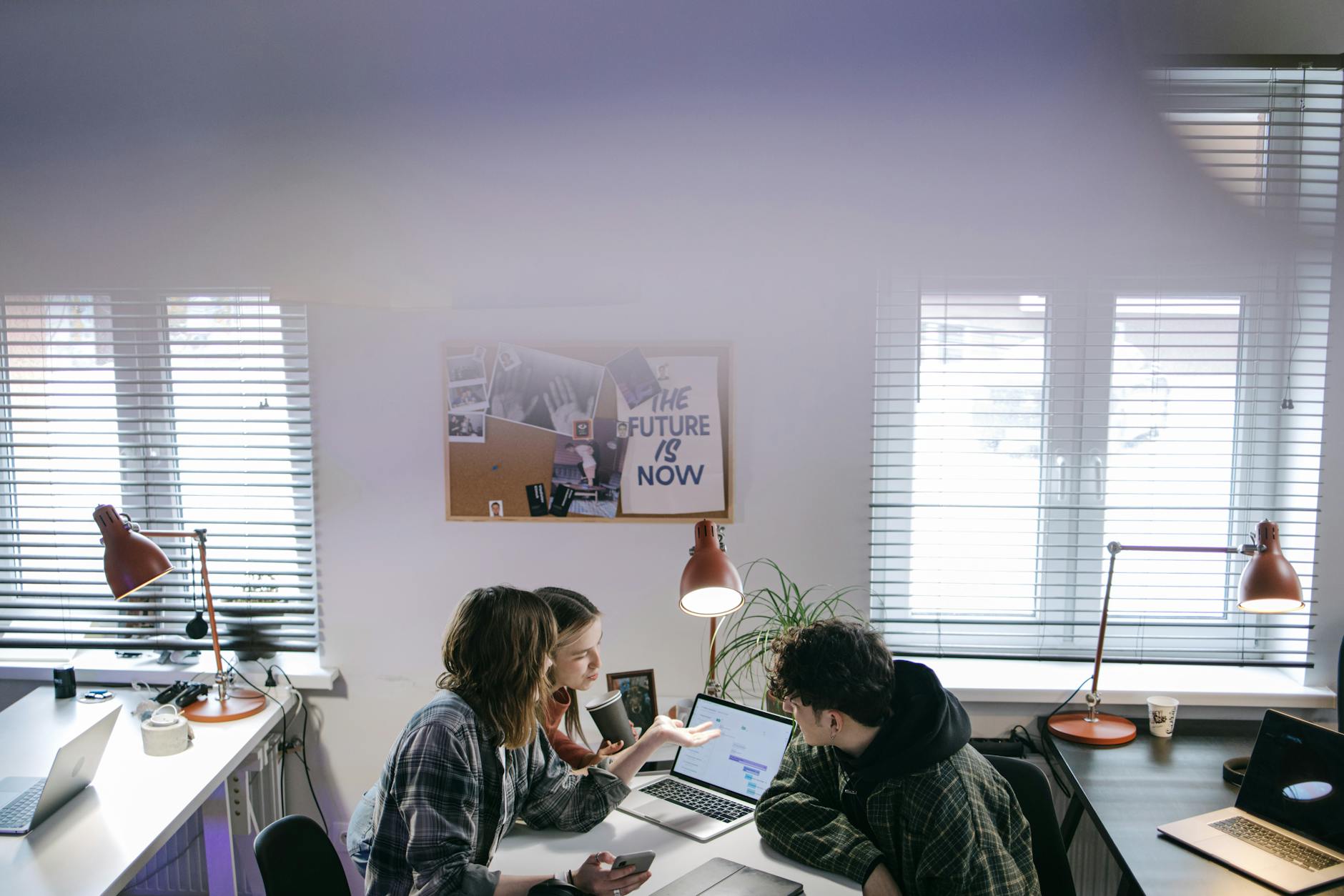A group of people discussing ideas around laptops in a bright, modern office space. - Photo by Ivan S on Pexels