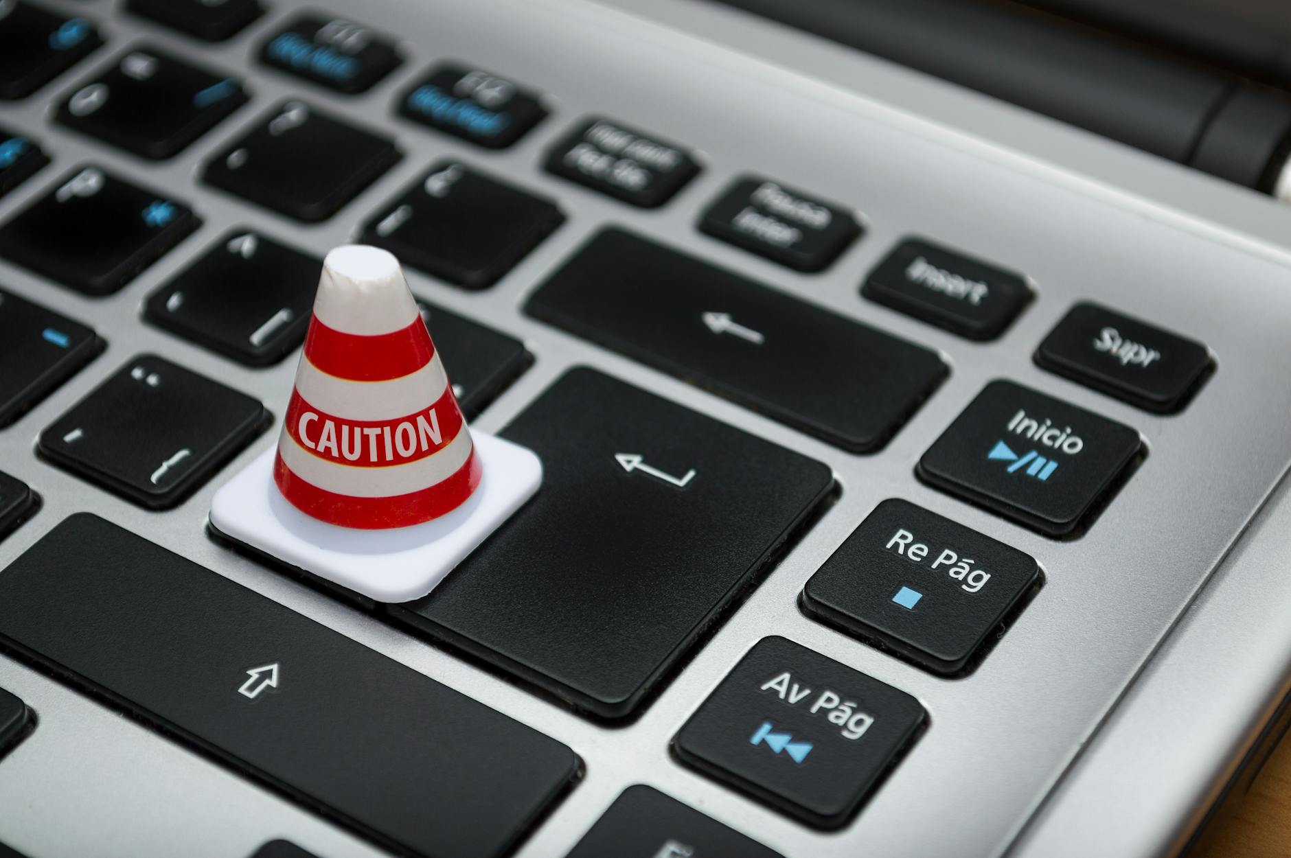 Miniature caution cone on a computer keyboard symbolizing data security and control. - Photo by Fernando Arcos on Pexels
