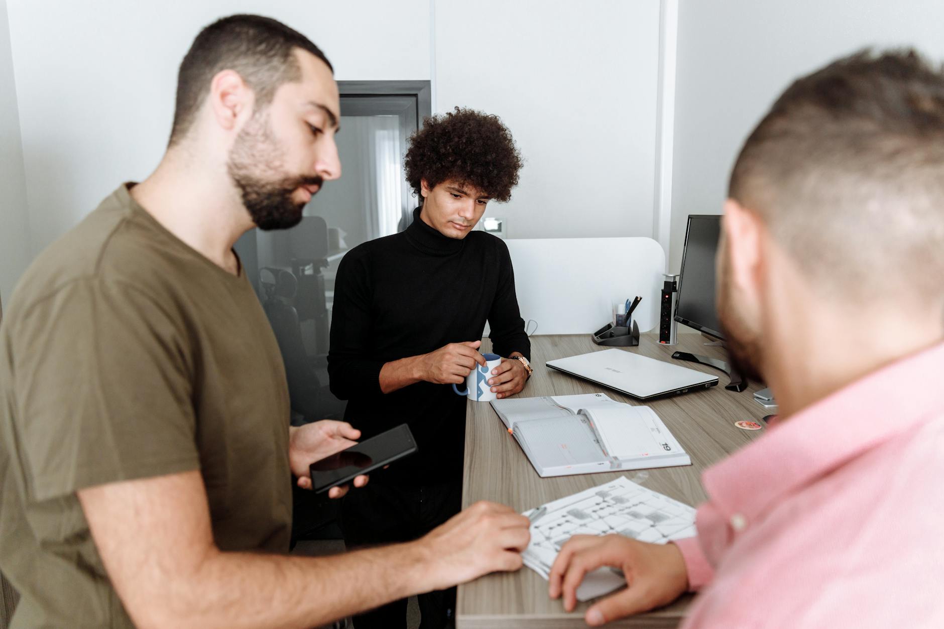 Three colleagues discussing work around a table in a modern office setting. - Photo by Thirdman on Pexels